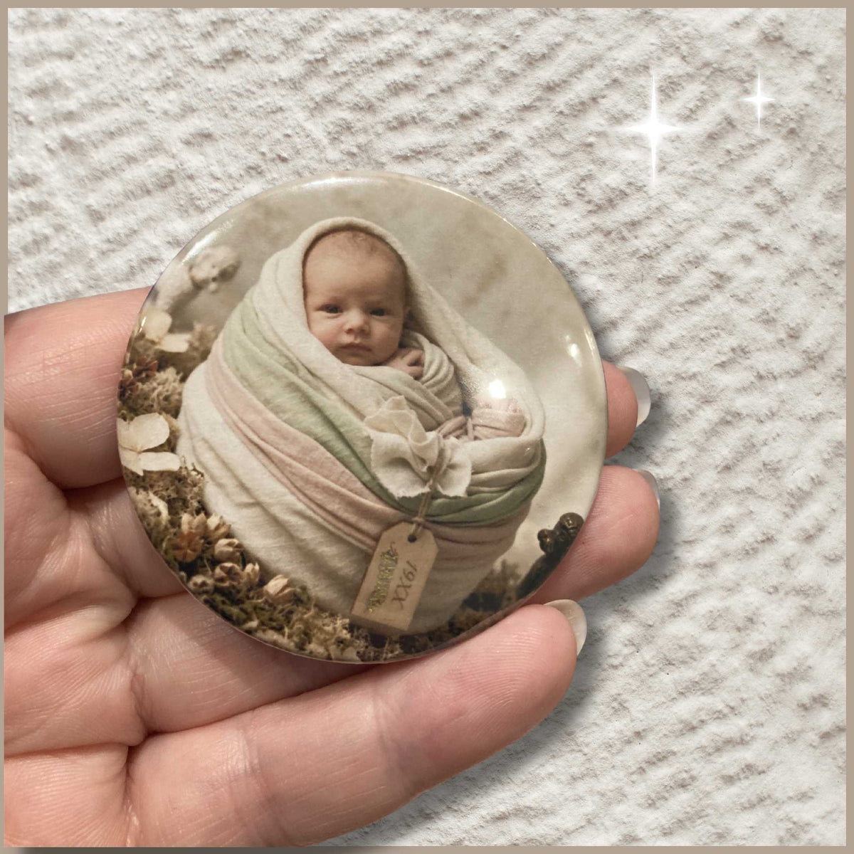 Ronde gepersonaliseerde foto button van 59 mm met een foto van een baby in een mandje van doeken.