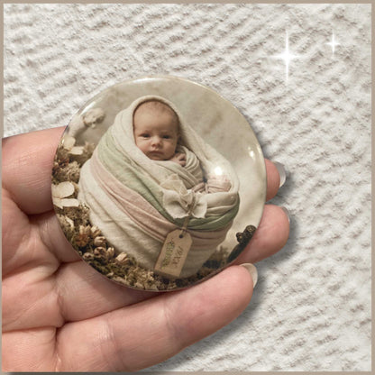 Ronde gepersonaliseerde foto button van 59 mm met een foto van een baby in een mandje van doeken.